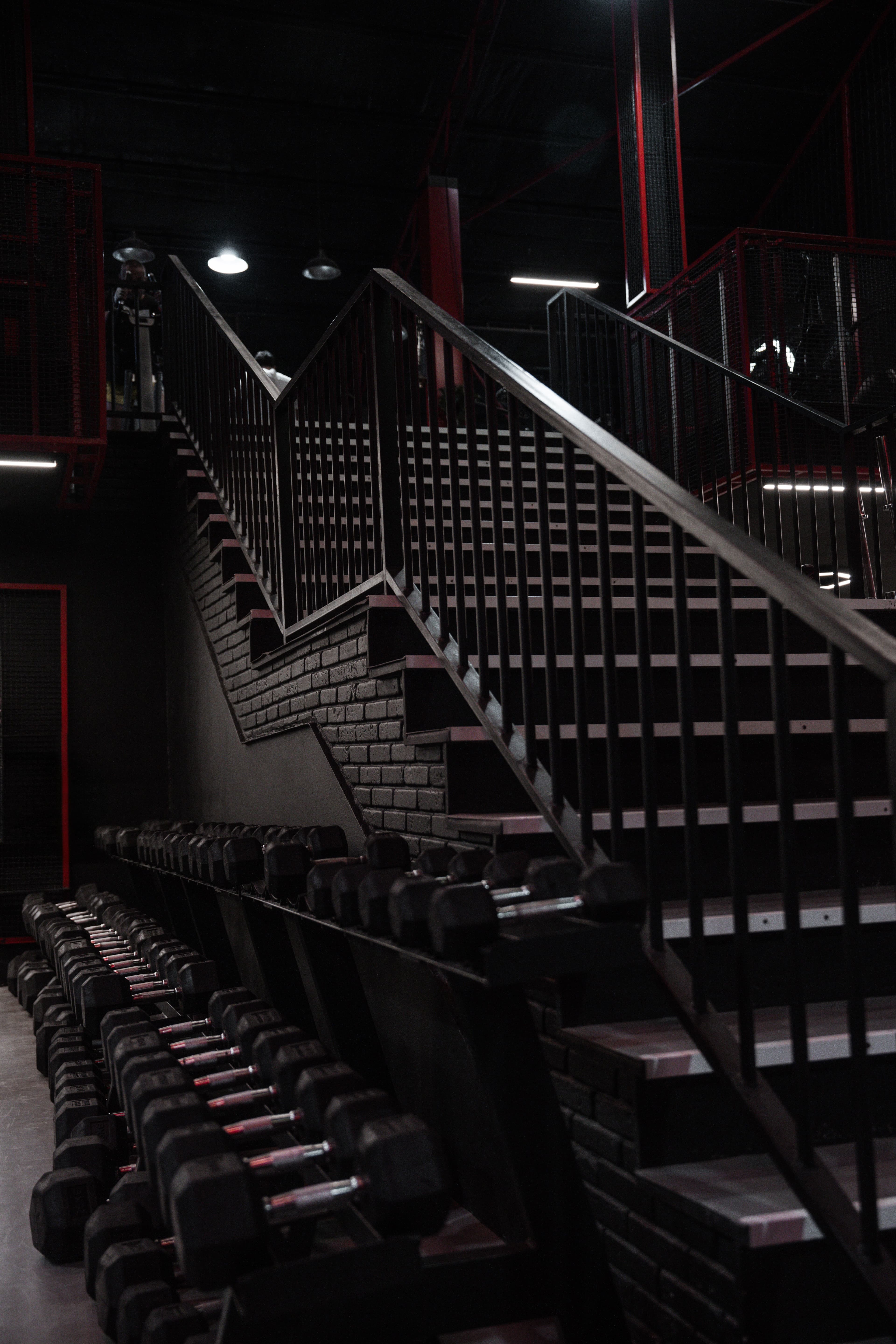 A dark staircase beside rows of dumbbells